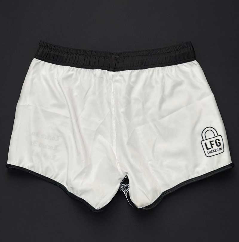 Rear view of white athletic shorts with black trim on a dark background